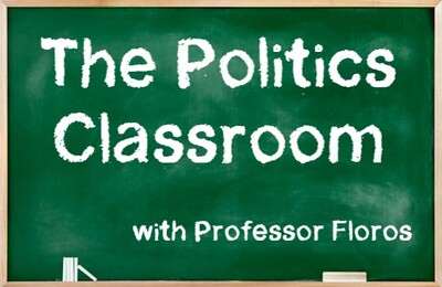 Green chalkboard with "The Politics Classroom with Professor Floros" written in white chalk. Also includes pieces of white chalk and a wooden eraser in the tray at the bottom of the board.