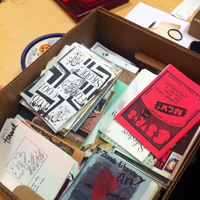 Box on a table filled with zines.
